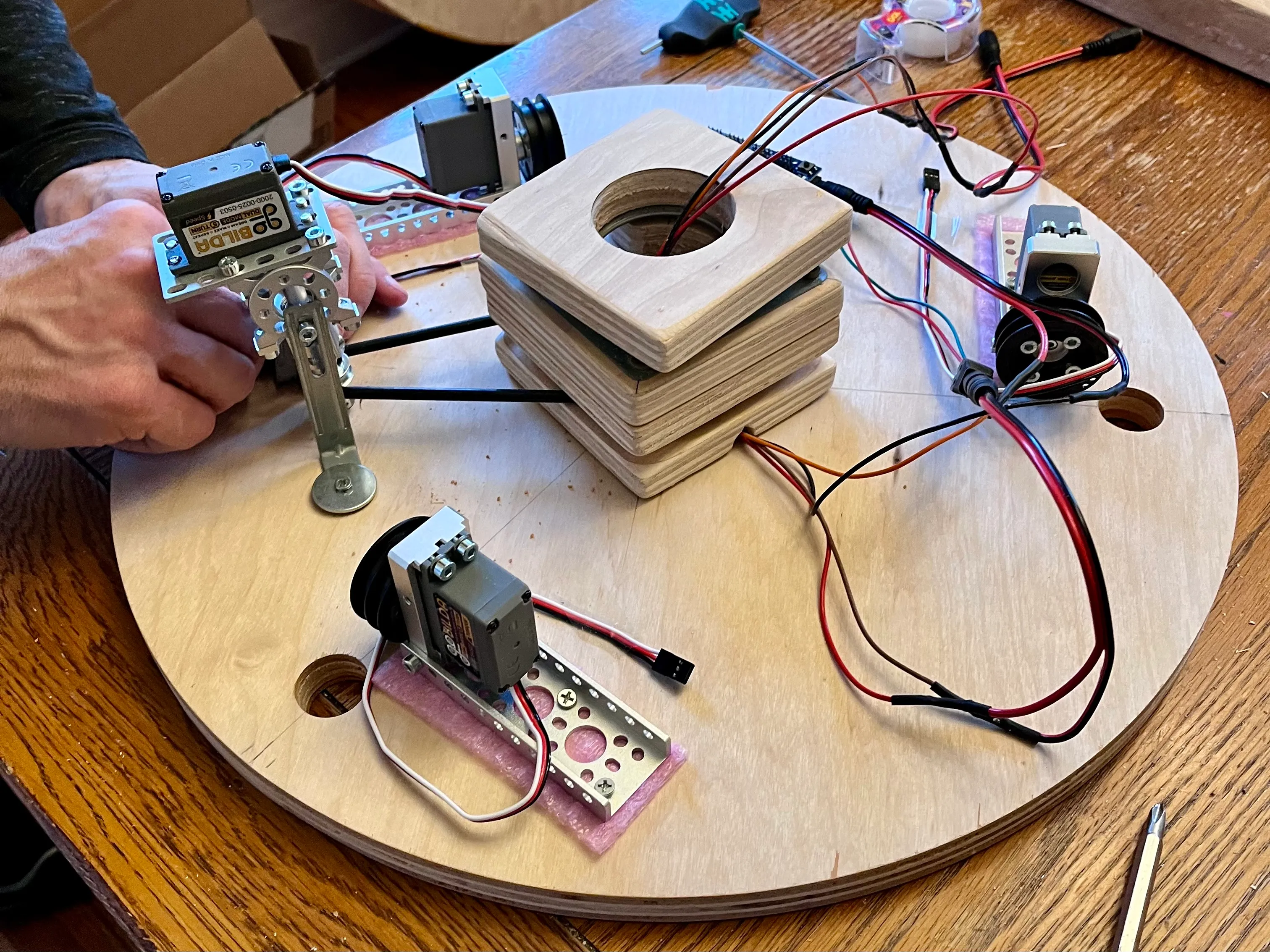 Servo motors, brackets, wiring, and a wooden bearing housing laid out for assembly