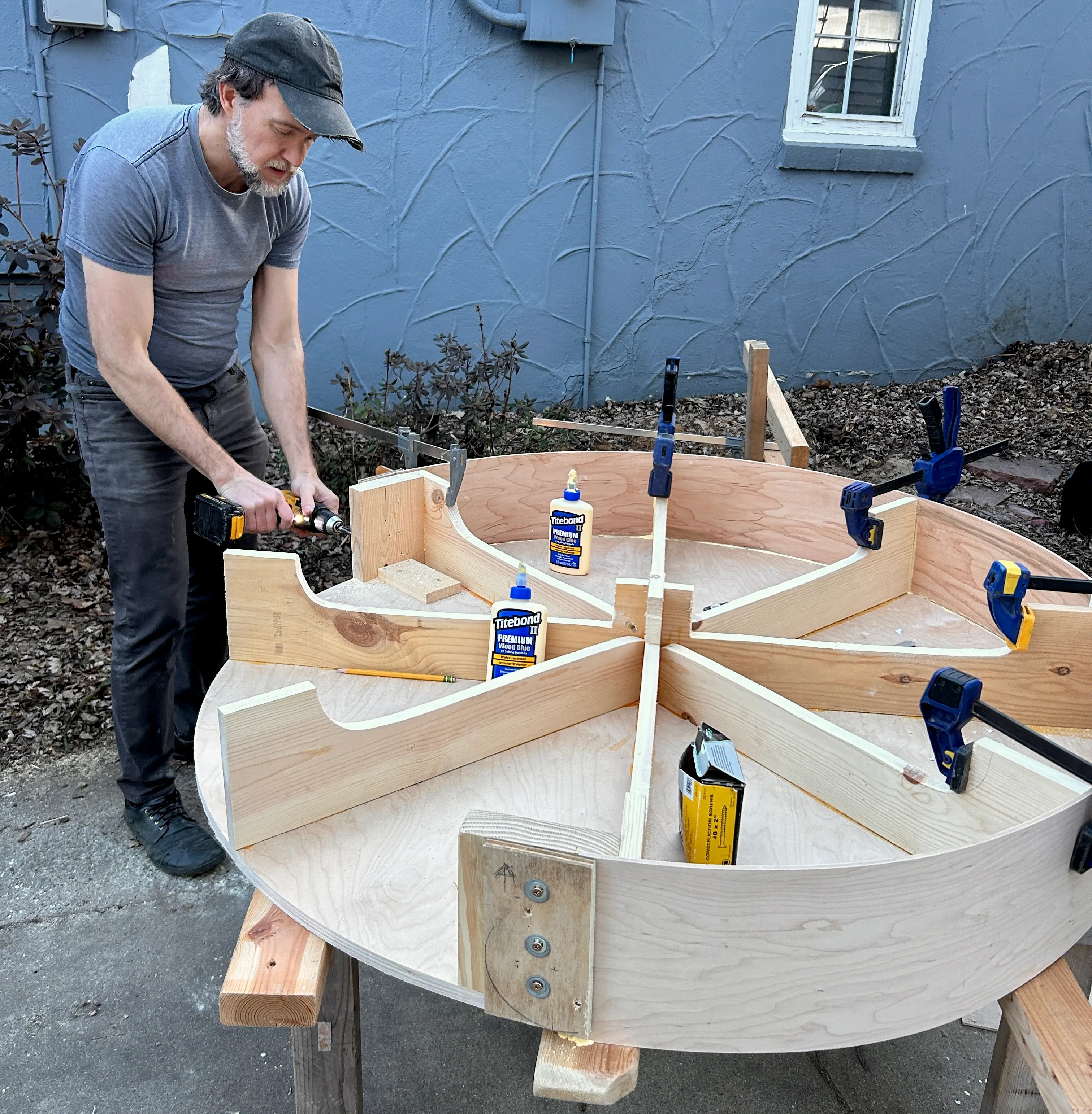 Fasteners being drilled into the assembled circular base while clamps remain in place